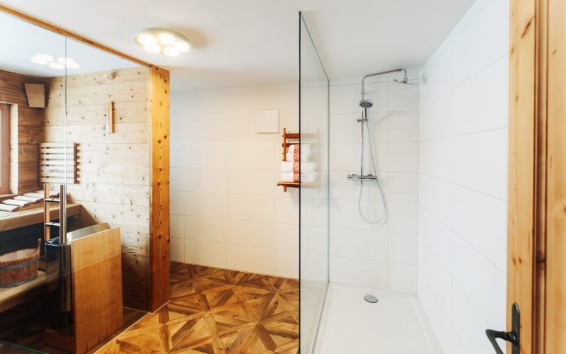 Interior of modern white bathroom with wood design. Home with mirror, sink and shower. Hotel bath room. House with towel, toilet furniture and decor. Wall and floor on background. Wooden decoration